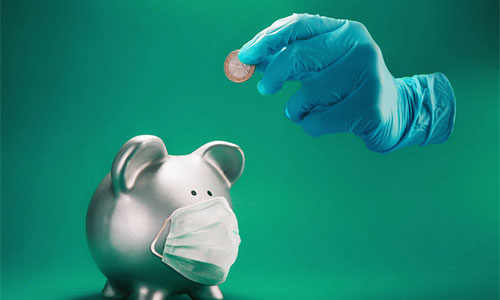 Blauer OP-Handschuh wirft ein Euro in ein silbernes Sparschwein mit Gesichtsmaske